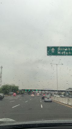 a street sign on the side of a road with cars driving by in the rain