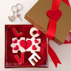 a gift box with two decorated cookies in the shape of crosses and hearts on it