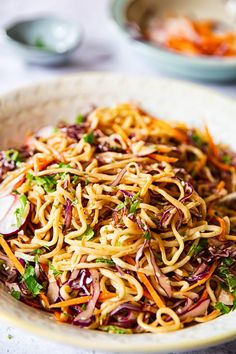 a bowl filled with noodles and vegetables on top of a table