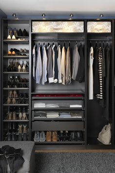 an open closet with clothes and shoes on the shelves, in front of a bed