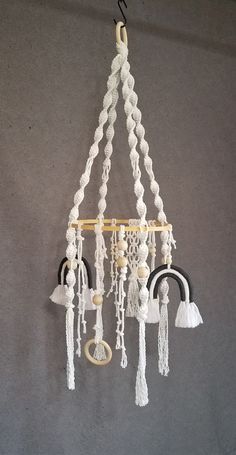 a wind chime hanging from a hook on a gray wall with white beads and tassels