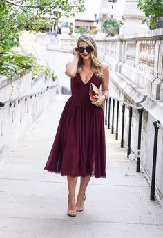 a woman in a purple dress is talking on her cell phone while walking down the sidewalk