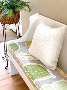 a white bench with a green plant on top of it next to a potted plant