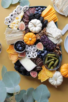 a platter filled with cheese, fruit and crackers on top of a table