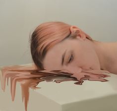 a woman laying down with her head on the edge of a table covered in melted chocolate