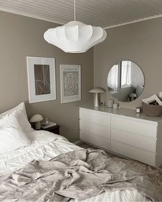 a bedroom with a bed, dresser and two mirrors on the wall next to each other