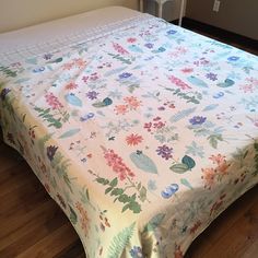 a bed with a floral bedspread on it in a room that has wood floors