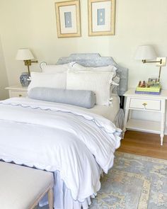 a white bed sitting next to two framed pictures