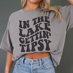 Hey there, Lake Lover! Are you ready to add some fun to your lakeside escapades? The On The Lake Gettin Tipsy Comfort Color Tee is the perfect blend of relaxation and a touch of humor for your waterfront adventures! Crafted from premium Comfort Color fabric, this tee feels as soft and comforting as a gentle breeze off the water. The playful On The Lake Gettin Tipsy graphic celebrates the carefree spirit of lake life, inviting you to kick back, relax, and enjoy a few drinks with friends. Whether Casual Spring Tops For Weekend Getaway, Summer Outdoor Tops With Letter Print, Summer Outdoor Top With Letter Print, Summer Tops With Letter Print For Outdoor, Casual Cotton Tops For Weekend Getaway, Casual Beach Season Tops For Outdoor, Casual Tops For Beach Season, Relaxed Fit Cotton Tops For Weekend Getaway, Weekend Getaway Cotton Crew Neck Top