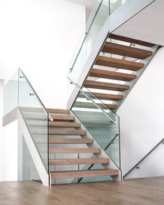 a stair case with glass railing and wooden handrails in a modern home setting