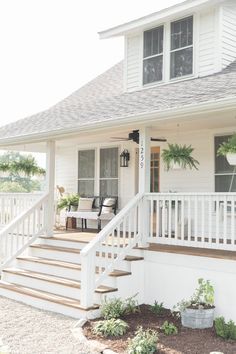 a white house with stairs leading up to the front door and covered porch area on either side