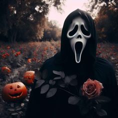 a person wearing a ghost mask and holding a rose in front of some pumpkins