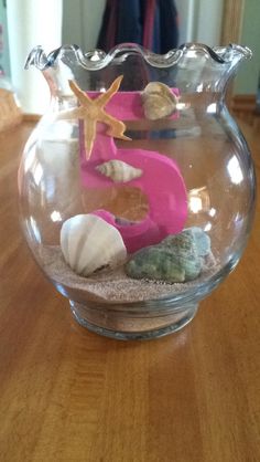 a glass bowl filled with sand and sea shells