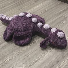 a purple stuffed animal laying on top of a wooden floor