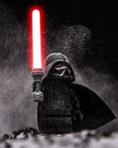 a lego darth vader standing in the rain with a red light on his head