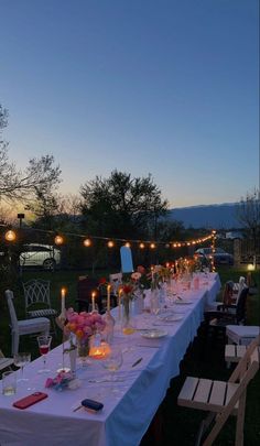 a long table is set up with candles and flowers for an outdoor dinner in the evening