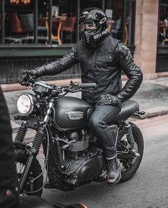 a man in black leather jacket and helmet sitting on a motorcycle