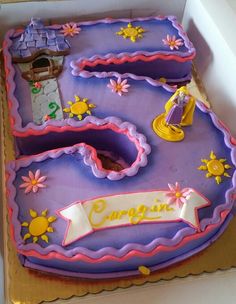 a birthday cake in the shape of a letter with princess figures on it and decorations