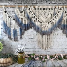 a wall hanging made out of macrame and tassels on a brick wall