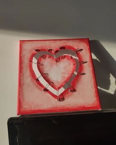 a red box with a heart cut out of it on top of a white table