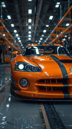 an orange sports car is parked in a large garage with lights on it's headlamps