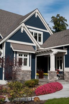 a blue house with white trim and stonework on the front porch is pictured in this image