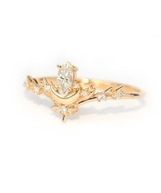 a yellow gold engagement ring with an oval diamond center and leaves on the band, set against a white background