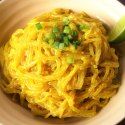 a white bowl filled with noodles and topped with scallions on a wooden table