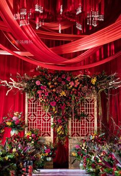 a room with red drapes and flowers on the wall, decorated with pink curtains