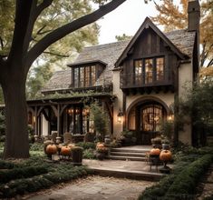 a house with pumpkins on the steps and trees around it in front of it