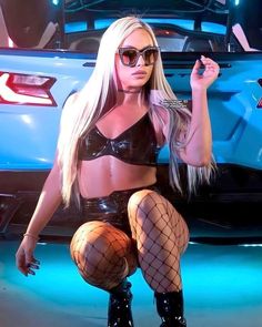 a woman in fishnet stockings and boots posing next to a car