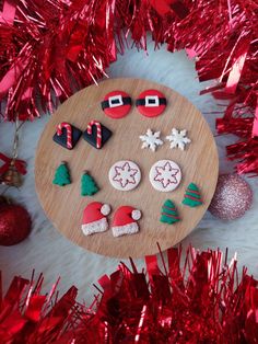 decorated cookies on a wooden plate surrounded by red tinsel