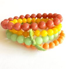 The perfect mix of citrus tones collide in this set of dark coral, light tangerine, fern green & golden yellow vintage beads. Bead sizes in this set are 10mm at the largest width. This stacking arm party set features 4 separate bracelets strung on a stretch material. One size fits most.Because the beads used in this piece are vintage, they will vary slightly from order to order but be in this general color way. 4 bracelets included in this set. One size fits most. Hand made in the US with su Orange Stackable Beaded Bracelets As Gift, Adjustable Orange Beaded Bracelets With 8mm Beads, Orange Bohemian Beaded Bracelets With 8mm Beads, Vintage Adjustable Beaded Bracelets With 8mm Beads, Orange Beaded Bracelets With 8mm Round Beads, Orange Stackable Beaded Bracelets For Gifts, Orange Stackable Jewelry With Round Beads, Stackable Orange Round Beaded Bracelets, Adjustable Orange Stackable Beaded Bracelets