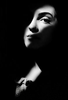 a black and white photo of a woman's face with her eyes closed in the dark