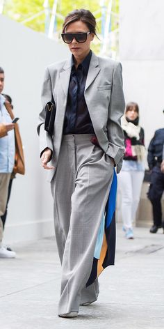 a woman in a suit and sunglasses walking down the street