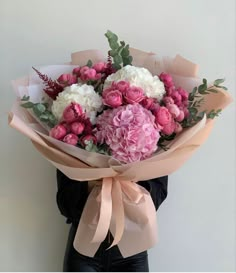 a woman holding a bouquet of pink and white flowers