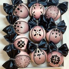 pink and black ornaments are arranged in a box with ribbon around the top, on display