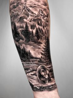 a man's arm with a bear and mountain scene on it