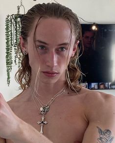 a shirtless woman holding a cell phone in her right hand and looking at the camera