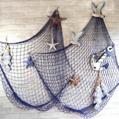 two blue net bags with starfish and seashells hanging on the wall next to each other