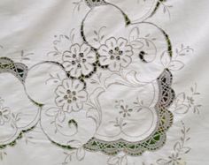 an embroidered white cloth with flowers and leaves on it, as well as green accents