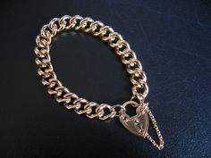 CLASSIC GOLD CHUNKY CHAIN BRACELET with LOCKET..  18K plated over Brass Core... Width of chain is 1.2 Cms  Bracelet Length is 18Cms for wrist size. Locket is non-removable and forms the clip to open to get the bracelet on and off... It measures 2.5 Cms long and there is a fine chain that connects both ends of the chain. TOP QUALITY and TOP LOOK !! Looks and feels very much like the real thing !! To Clean :- wash in warm soapy water and dry with  Hair dryer.. KEEP AWAY FROM PERFUMES !! Gold-tone Gold Plated Charm Bracelet With Adjustable Chain, Heart-shaped Metal Charm Bracelet With Adjustable Chain, Yellow Gold Heart-shaped Chain Bracelet With Charms, Gold-tone Chain Link Charm Bracelet, Gold-tone Adjustable Chain Charm Bracelet In Brass, Bracelet With Heart, Chain Top, Filigree Pendant, Rose Quartz Beads