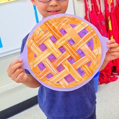 a young boy holding up a paper pie