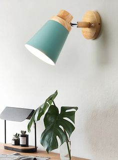 a green lamp on the wall next to a potted plant