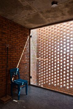 a room with a brick wall and a chair in front of an open glass door