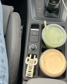 there is a cup holder in the center console of a car with drinks and snacks