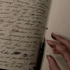 a hand is holding a pen and writing on a piece of paper with cursive writing