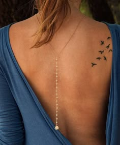 the back of a woman's neck with birds on it and a star tattoo