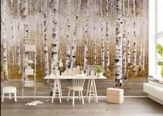 a room with a table and chairs in front of a wall that has birch trees on it