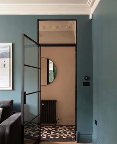 an open door leading to a living room with a black couch and mirror on the wall